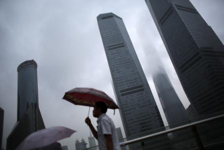 © Reuters/Carlos Barria. A man walks in the rain along the financial district of Pudong in downtown Shanghai, Aug. 18, 2014.