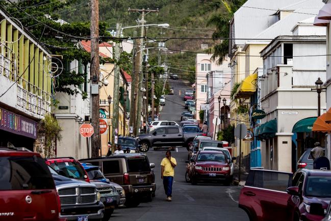 © Bloomberg. A pedestrian speaks on a mobile device while walking along a street in the town of Christiansted in Saint Croix, Virgin Islands.