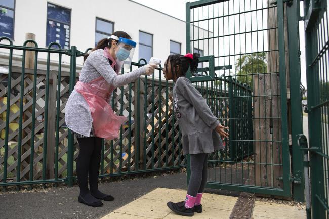 © Bloomberg. A member of staff takes a child's temperature at a school in London. Photographer: Dan Kitwood/Getty Images