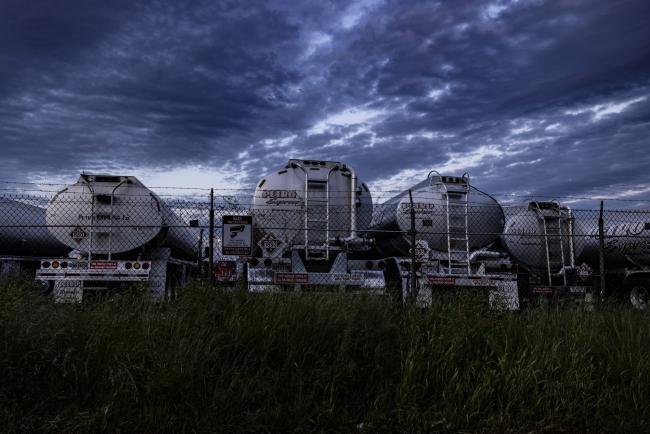 © Bloomberg. Petroleum tanker trucks parked near fuel storage tanks connected to the Colonial Pipeline Co. system in an industrial area of the Port of Baltimore in Baltimore, Maryland, U.S., on Tuesday, May 11, 2021. Fuel shortages are expanding across several U.S. states in the East Coast and South as filling stations run dry amid the unprecedented pipeline disruption caused by a criminal hack.