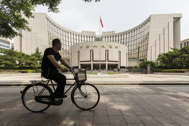 © Bloomberg. A man rides a bicycle past the People's Bank of China (PBOC) headquarters in Beijing, China, on Friday, June 7, 2019. China's central bank governor said there's 