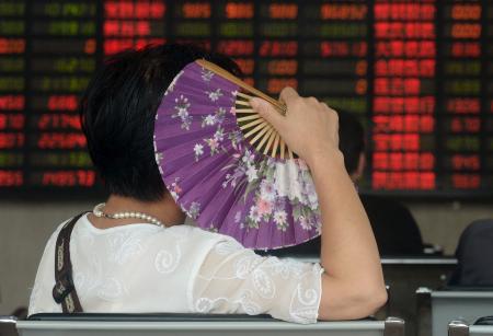 © Reuters. An investor holds a fan as she looks at stock information on an electronic board at a brokerage house in Shanghai on Aug. 26, 2015. China's fresh monetary easing triggered stock market gyrations on Wednesday, with key indexes ending down for a fifth straight session after swinging more than 3 percent in both directions in extreme volatility.
