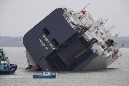 © Reuters/Peter Nicholls. The cargo ship Hoegh Osaka lies on its side after being deliberately ran aground on the Bramble Bank in the Solent estuary, near Southampton in southern England on Jan. 5, 2015. The vessel was deliberately run aground on Saturday evening after it began to list, according to its owners Hoegh Autoliners.