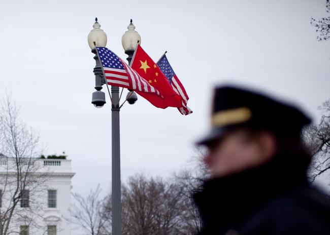 © Bloomberg. Flags of the U.S. and China fly outside the White House as a member of the Secret Service stands guard in Washington, D.C., U.S., on Monday, Jan. 17, 2011. Hu Jintao, president of China, arrives in Washington today for his first state visit to the U.S. with Chinese executives. Photographer: Bloomberg/Bloomberg