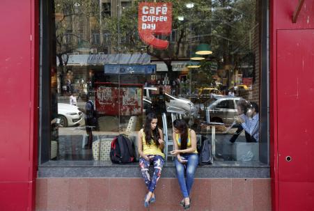 © Reuters/Shailesh Andrade. Girls sit at the window of a Cafe Coffee Day outlet in Mumbai, February 25, 2015. The firm behind Cafe Coffee Day, India's biggest homegrown coffee chain, is set for a market debut that could value it at alt=