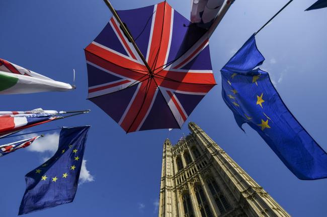 © Bloomberg. An umbrella featuring the design of the Union flag, also known as the Union Jack, stands near European Union (EU) flags outside the Houses of Parliment in London, U.K., on Tuesday, Oct. 22, 2019. U.K. Prime Minister Boris Johnson will find out Tuesday evening whether he has any chance of getting his Brexit deal through Parliament -- and whether he can do it ahead of his Oct. 31 deadline. Photographer: Chris J. Ratcliffe/Bloomberg