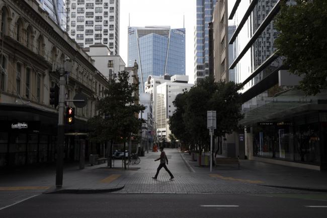 © Bloomberg. A pedestrian crosses a road in an empty street during a lockdown imposed due to the coronavirus in Auckland, New Zealand, on Thursday, March 26, 2020. Every household will be required to go into self-isolation, all non-essential businesses will close and schools will be shut, Prime Minister Jacinda Ardern said on March 23 in Wellington. Photographer: Brendon O'Hagan/Bloomberg