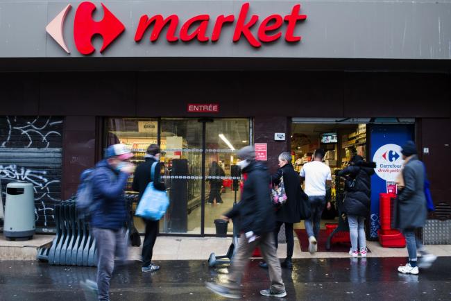 © Bloomberg. Pedestrians pass a Carrefour Market supermarket, operated by Carrefour SA, in Paris, France, on Wednesday, Jan. 13, 2021. Alimentation Couche-Tard Inc., the Canadian convenience-store operator that owns the Circle K chain, is exploring a takeover of French grocer Carrefour SA, a deal that would create a trans-Atlantic retail giant.