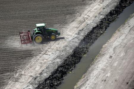© Reuters. A tractor plows a field next to a water-starved canal in Los Banos, California, United States May 5, 2015. In the United States and across the world, enduring drought and water scarcity are straining operations of America's major food companies.