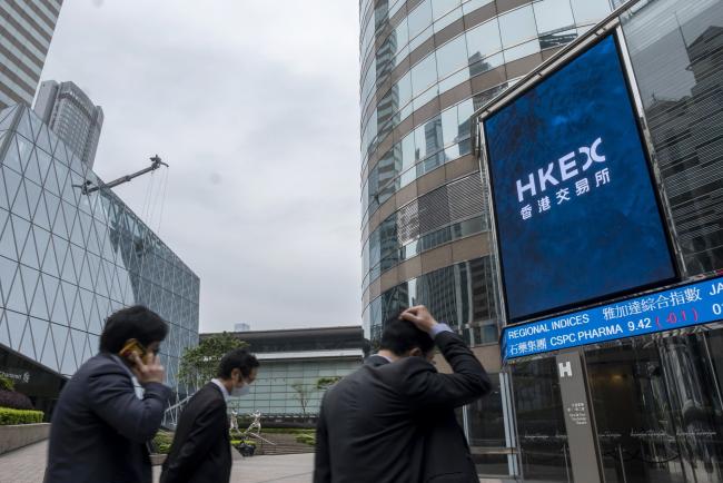 © Bloomberg. Pedestrians walk past the Exchange Square complex, which houses the Hong Kong Stock Exchange, in Hong Kong, China, on Tuesday, March 23, 2021. Baidu's stock offering in Hong Kong today marks an unlikely resurgence for founder Robin Li, who has fought his way back to relevance in China’s technology industry after squandering a near-monopoly in search. Photographer: Paul Yeung/Bloomberg