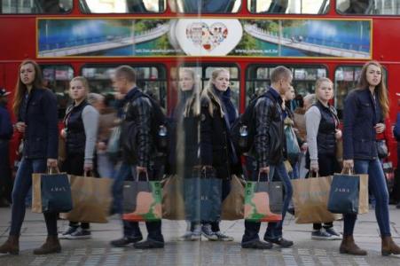 © Reuters/Luke MacGregor. Shoppers are reflected in a window as they carry bags along Oxford street during the final weekend of shopping before Christmas in London on Dec. 20, 2014.