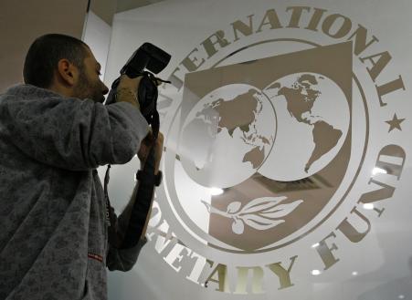 © Reuters/Bogdan Cristel. A photographer takes pictures through a glass carrying the International Monetary Fund (IMF) logo during a news conference in Bucharest, March 25, 2009.