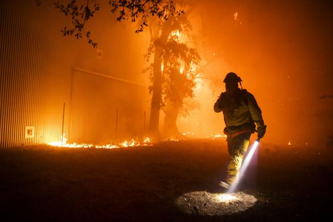 © Bloomberg. Bloomberg Best of the Year 2019: A firefighter uses a flashlight to search the perimeter of a building at the Soda Rock Vineyards during the Kincade fire in Healdsburg, California, U.S., on Sunday, Oct. 27, 2019.