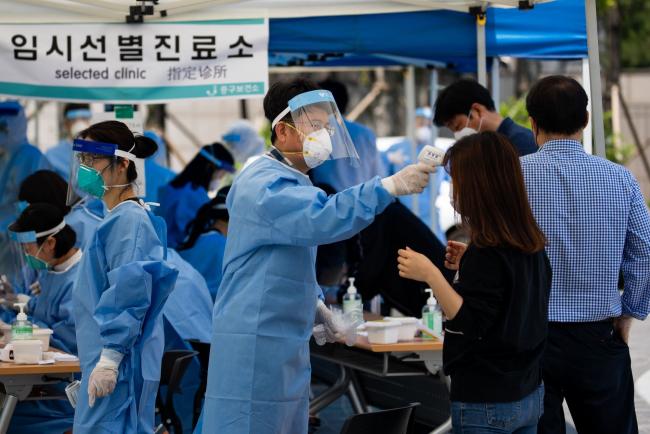 © Bloomberg. A medical worker in protective gear checks a temperature of a woman at a temporary coronavirus testing station in Seoul, South Korea, on Friday, May 29, 2020. In the wake of the new cluster, the South Korean government said it was temporarily closing public museums, parks and galleries in the Seoul metropolitan area and may consider stronger social distancing measures if the situation worsens.