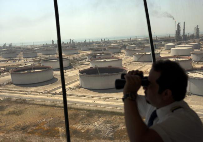 © Bloomberg. An employee uses binoculars to look out towards the Arabian Sea in the Port Control Center at Saudi Aramco's Ras Tanura oil refinery and terminal in Ras Tanura, Saudi Arabia, on Monday, Oct. 1, 2018. Saudi Aramco aims to become a global refiner and chemical maker, seeking to profit from parts of the oil industry where demand is growing the fastest while also underpinning the kingdoms economic diversification. Photographer: Bloomberg/Bloomberg