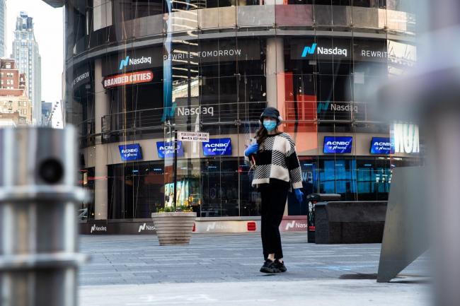 © Bloomberg. A pedestrian wearing a protective mask walks past the Nasdaq MarketSite in the Times Square neighborhood of New York. Photographer: Jeenah Moon/Bloomberg