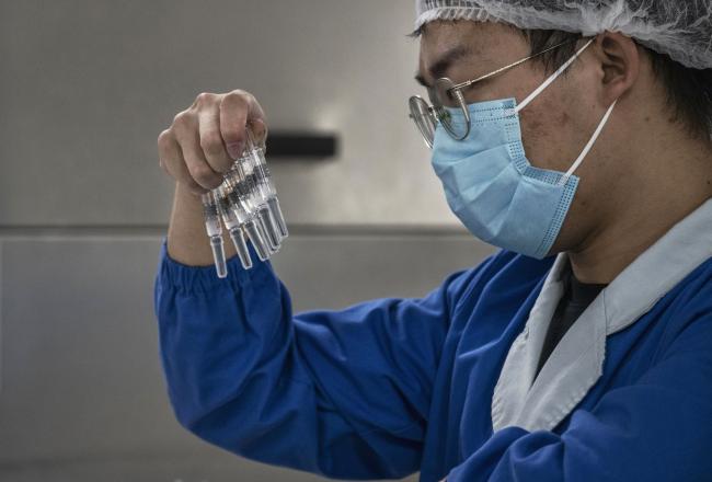 © Bloomberg. BEIJING, CHINA - SEPTEMBER 24: A worker checks syringes of the potential vaccine CoronaVac on the production line at Sinovac Biotech where the company is producing their potential COVID-19 vaccine CoronaVac during a media tour on September 24, 2020 in Beijing, China. Sinovacs inactivated vaccine candidate, called CoronaVac, is among a number of companies in the global race to control the coronavirus pandemic. The company is running Phase 3 human trials in four countries and ramping up production to 300 million doses per year at a new manufacturing facility south of Beijing. A lack of domestic coronavirus cases in China has meant that companies developing vaccines have shifted their focus overseas to conduct trials to gather the volume of data necessary to win regulatory approvals. When Chinas government launched an emergency use program in July to vaccinate groups of essential workers, Sinovacs chief executive says the company supplied tens of thousands of doses, even as trials are still underway. About 90% of Sinovacs employees have chosen to receive injections of CoronaVac, which is one of eight Chinese vaccine candidates in human trials. The company is also seeking approval to begin clinical trials with teenagers and children as young as age 3.(Photo by Kevin Frayer/Getty Images)