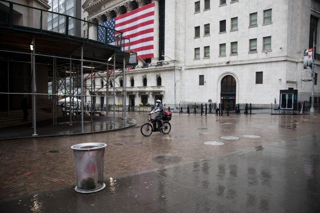 © Bloomberg. A food delivery worker wearing a protective mask bikes past the New York Stock Exchange (NYSE) in New York, U.S., on Tuesday, April 21, 2020. Treasury futures ended Tuesday mixed, with front-end yields slightly cheaper on the day and rest of the curve richer, yet off session lows reached during U.S. morning. Photographer: Michael Nagle/Bloomberg