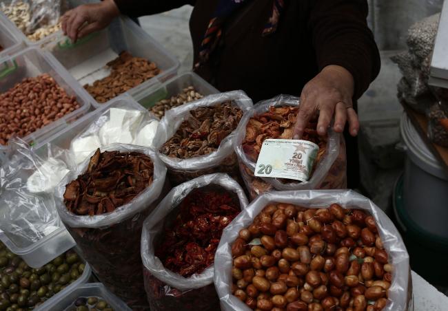 © Bloomberg. A market trader handles a 20 lira banknote on her food stall in Istanbul.