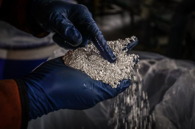 © Bloomberg. A worker inspects silver granules at a smelter in Sydney.