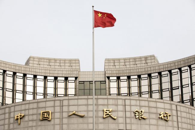 © Bloomberg. A Chinese flag flies in front of the People's Bank of China headquarters in Beijing, China, on Monday, Jan. 7, 2019. The central bank on Friday announced another cut to the amount of cash lenders must hold as reserves in a move to release a net 800 billion yuan ($117 billion) of liquidity and offset a funding squeeze ahead of the Chinese New Year. Photographer: Giulia Marchi/Bloomberg