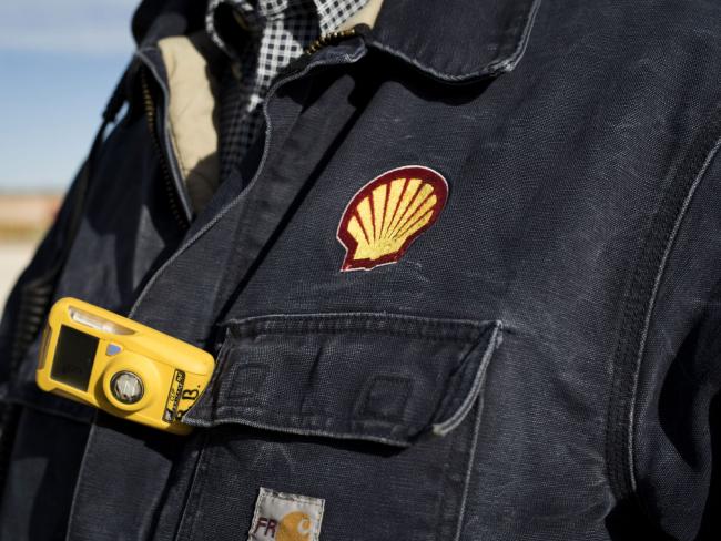 © Bloomberg. A Royal Dutch Shell Plc representative wears a shirt with the company's logo at an oil rig site near Mentone, Texas, U.S., on Thursday, March 2, 2017. Exxon Mobil Corp., Royal Dutch Shell and Chevron Corp., are jumping into American shale with gusto, planning to spend a combined $10 billion this year, up from next to nothing only a few years ago. Photographer: Matthew Busch/Bloomberg