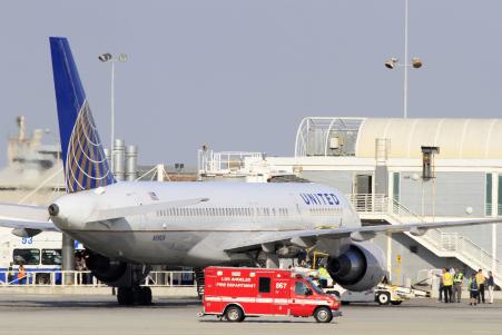 © Reuters/Jonathan Alcorn. A Los Angeles Fire Department Paramedic truck drives past a United Airlines plane from New York's JFK airport, that was diverted to a remote gate after landing at LAX, after a passenger on the flight exhibited flu-like symptoms, in Los Angeles, California on Oct. 12, 2014.