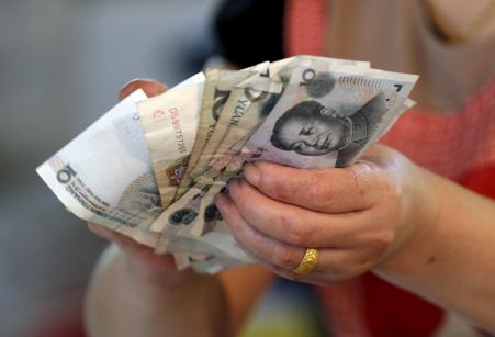 © Reuters/Jason Lee. On Monday, China's currency -- the yuan -- may join the International Monetary Fund's basket of reserve currencies, known as Special Drawing Rights. Pictured: A vendor holds Chinese Yuan notes at a market in Beijing, August 12, 2015.