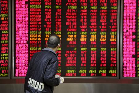 © Reuters/Li Sanxian. An investor walks past in front of an electronic board showing stock information at a brokerage house in Beijing, Nov. 17, 2015.