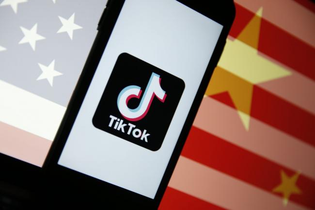 © Bloomberg. The TikTok logo sits displayed on a smartphone in front of an image of the national flags of China and the U.S. in this arranged photograph in London, U.K., on Monday, Aug. 3, 2020. TikTok has become a flash point among rising U.S.-China tensions in recent months as U.S. politicians raised concerns that parent company ByteDance Ltd. could be compelled to hand over American users’ data to Beijing or use the app to influence the 165 million Americans, and more than 2 billion users globally, who have downloaded it.