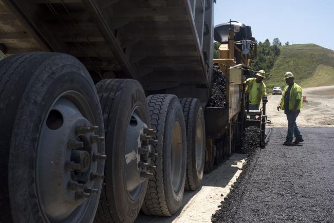 © Bloomberg. A truck dumps asphalt as contractors pave a road during highway construction between U.S. Route 23 and U.S. Route 52 near Portsmouth, Ohio, U.S., on July 26, 2017. The U.S. Census Bureau is scheduled to release construction spending figures on August 1. Photographer: Ty Wright/Bloomberg