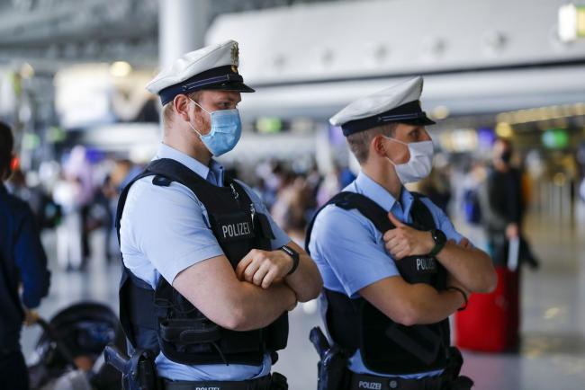 © Bloomberg. Police officers wear protective face masks as they monitor departure hall travelers as Deutsche Lufthansa AG and airport operator Fraport AG showcase new coronavirus safety measures at Frankfurt Airport in Frankfurt, Germany, on Wednesday, June 17, 2020. Deutsche Lufthansa said a low turnout at its extraordinary general meeting next week is placing its 9 billion-euro ($10 billion) German bailout at risk of falling apart.