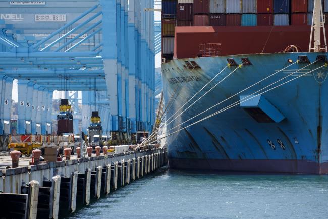 © Bloomberg. Shipping containers are unloaded from the Maersk Edinburgh cargo ship at the APM shipping terminal in the Port of Los Angeles in Los Angeles, California, U.S., on Tuesday, May 7, 2019. The terminal is planning to replace diesel trucks and human workers. It has already ordered an electric, automated carrier from Finnish manufacturer Kalmar, part of the Cargotec Corp., that can fulfill the functions of three kinds of manned diesel vehicles: a crane, top-loader and truck. Photographer: Patrick T. Fallon/Bloomberg