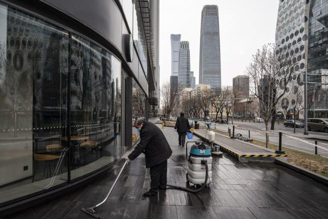 © Bloomberg. A worker cleans a sidewalk outside a shopping mall in Beijing, China, on Saturday, March 6, 2021. China, the world's biggest car market, aims to boost auto sales and add more charging facilities for electric vehicles this year. Photographer: Qilai Shen/Bloomberg