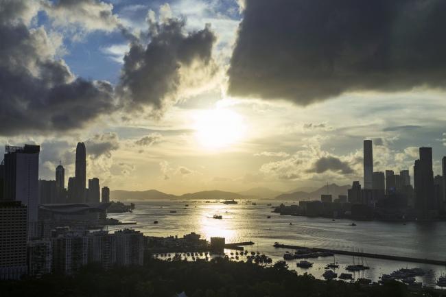 © Bloomberg. Buildings are silhouetted as the sun sets in Hong Kong, China, on Thursday, June 4, 2020. Hong Kong is facing renewed tensions following months of unprecedented pro-democracy protests that kicked off soon after last June's vigil. Demonstrations have again increased in recent weeks as China announced that it would impose sweeping national security legislation on the city, raising concerns about whether it would maintain key freedoms from the mainland. Photographer: Justin Chin/Bloomberg