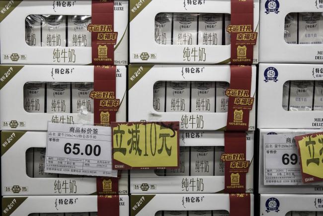 © Bloomberg. A price tag and discount signs are seen on cartons of China Mengniu Dairy Co. pure milk inside a grocery store in an arranged photograph in Beijing, China, on Friday, Jan. 6, 2017. Mengniu, the country's second-largest dairy company, offered to buy out China Modern Dairy Holdings Ltd. for HK$6.92 billion ($892 million) to gain control over the country's biggest raw milk supplier amid a national push to improve food safety. Photographer: Qilai Shen/Bloomberg