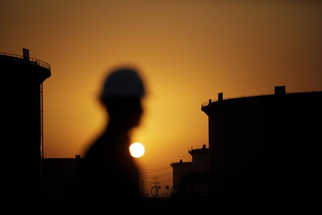 © Bloomberg. The sun sets beyond crude oil storage tanks at Saudi Aramco's Ras Tanura oil refinery. Photographer: Simon Dawson/Bloomberg