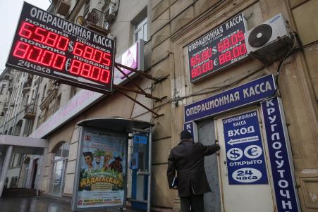 © Reuters. A man walks into a building, past a board showing currency exchange rates in Moscow, on Dec. 16, 2014. Russia's ruble extended losses in afternoon trading on Tuesday, joining a handful of oil-producing nations whose currencies have slipped along with the falling price of crude oil.