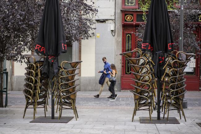 © Bloomberg. Pedestrians walk past stacked chairs outside a closed cafe in Plaza del Angel in Madrid, Spain, on Thursday, Oct. 8, 2020. France, Spain and the Czech Republic posted record increases in coronavirus cases, underscoring growing alarm in Europe as it struggles to control the pandemic. Photographer: Paul Hanna/Bloomberg