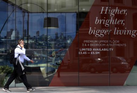 © Reuters/Luke MacGregor. A man walks past the signage of a new property development advertising apartments for 5.5 million pounds sterling in central London on July 2, 2014.